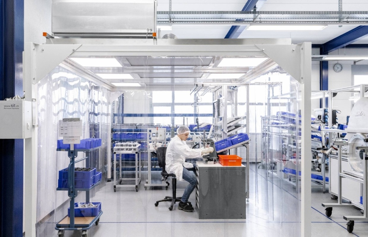 Mann montiert in Schutzkleidung mechanische Fertigungskomponenten in Reinraum nach ISO13485