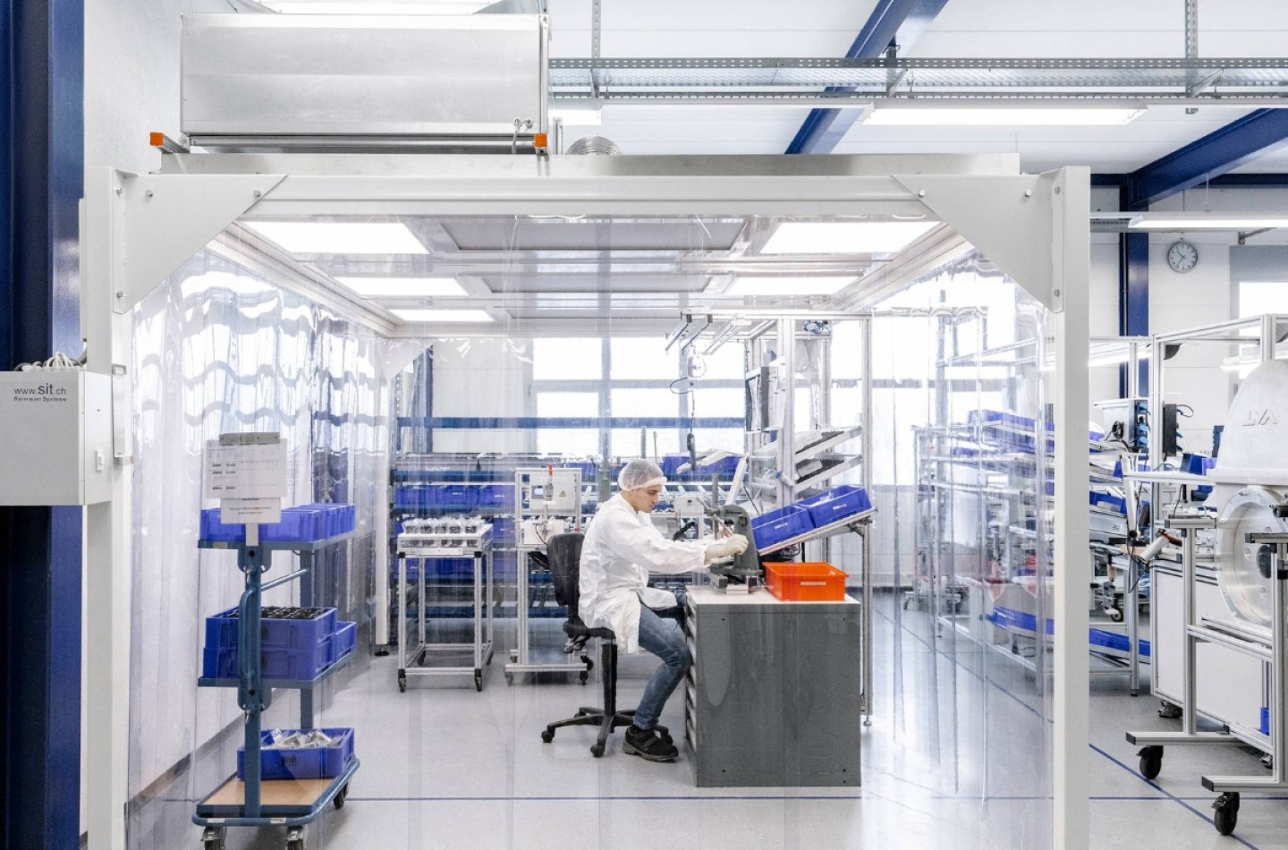 Mann montiert in Schutzkleidung mechanische Fertigungskomponenten in Reinraum nach ISO13485